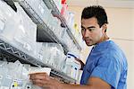 Male nurse standing by shelves with medical supply, low angle view