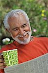 Elderly man reading newspaper outdoors