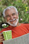 Elderly man reading newspaper outdoors, portrait