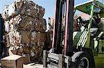 Stacks of cardboard boxes in recycling centre and forklift truck
