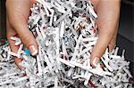 Woman holding heap of shredded paper, close-up of hands