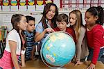 Group of pupils and teacher looking at the globe