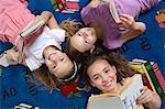 School girls reading books on floor in library