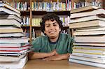 School boy sitting at desk with books in library, portrait