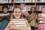 School children holding books in library, portrait