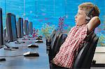 School boy wearing headphones, relaxing in computer room