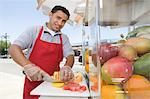 Portrait of male street vendor chopping fruit