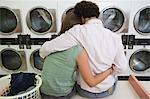 Young couple washing clothes at launderette