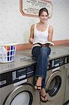 Portrait de jeune femme assise sur la machine à laver