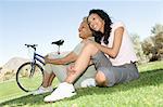 Mother and daughter sit in park with mountain bikes