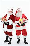 Two men dressed as Santa Claus holding gifts