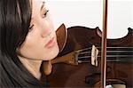 Young Asian woman concentrates on playing the violin