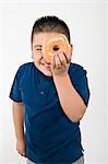 Pre-teen (10-12) boy holding doughnut over eye