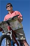 Reifer Mann steht Blick auf Karte mit Mountainbike