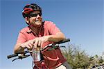 Älterer Mann in Radfahren Helm lehnt sich auf Fahrrad Lenker