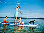 Woman on paddle board with kids and dog