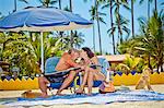 Man and woman kissing while seated in beach chairs