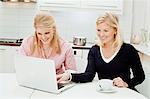 Deux jeunes femmes à l'aide d'ordinateur portable dans la cuisine