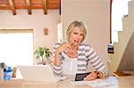 Woman working at home office with computer and bills