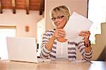 Frau im Büro zu Hause halten Rechnungen und Blick auf laptop