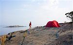 Woman camping on rock by sea