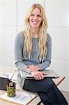 Portrait of woman holding laptop in office