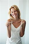 Young woman holding pregnancy test, smiling