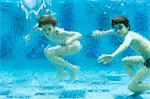 Brother and sister swimming underwater in swimming pool