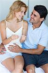 Husband putting hand on wife's abdomen after reading result of pregnancy test