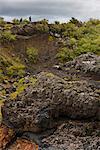Tourists walking along hillside of lava field, Iceland
