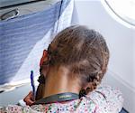 Girl writing on airplane, rear view