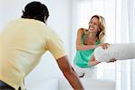 Young woman pillow fighting husband