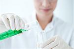 Scientist pouring liquid from graduated cylinder to test tube