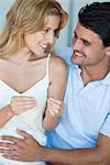 Couple looking at pregnancy test, man with hand on woman's abdomen