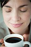 Mid-adult woman smelling cup of coffee