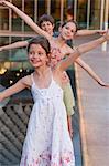 Children standing in a row on edge of pond with arms outstretched