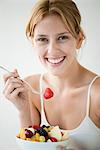 Young woman eating fruit salad, portrait