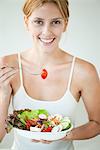 Young woman eating bowl of salad