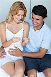 Couple looking at pregnancy test, man with hand on woman's abdomen