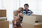 Couple sitting in living room with cardboard boxes