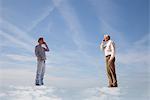 Men standing on clouds, using cell phones