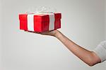 Woman's arm holding out gift box, cropped