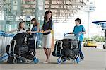 Famille debout à l'extérieur de l'aéroport avec des bagages