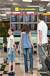 Family looking at arrival departure board in airport