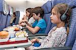 Girl watching movie on airplane, airline meal on tray table