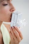 Woman kissing wrapped gift, eyes closed