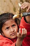 Young girl checking to see if the communal village water tap has water, as it runs dry daily, Pokhara, Nepal, Asia