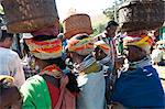 Bonda tribeswomen wearing traditional beaded caps and metal necklaces, with baskets on their heads at weekly market, Rayagader, Orissa, India, Asia