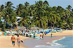 Tourists stroll whilst local fishermen work on this popular surf beach, Arugam Bay, Eastern Province, Sri Lanka, Asia