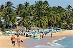 Touristes se promener alors que les pêcheurs locaux travaillent sur cette plage de surf populaire, Arugam Bay, Province orientale, Sri Lanka, Asie